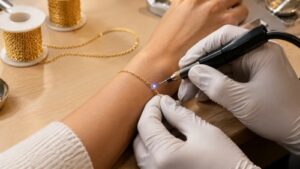 Jeweller welding a fine gold permanent bracelet closed on a customer's wrist