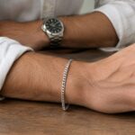 Man wearing a slim sterling silver bracelet on his wrist with a rolled shirt cuff