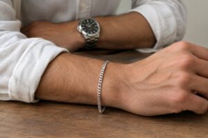 Man wearing a slim sterling silver bracelet on his wrist with a rolled shirt cuff