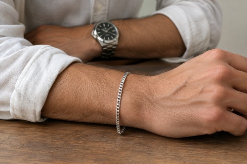 Man wearing a slim sterling silver bracelet on his wrist with a rolled shirt cuff