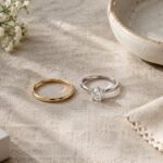 Slim promise ring next to a diamond solitaire engagement ring on linen, showing the size and design difference