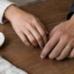 Two hands showing a promise ring worn on the left ring finger and a silver promise ring on the right ring finger