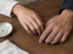 Two hands showing a promise ring worn on the left ring finger and a silver promise ring on the right ring finger
