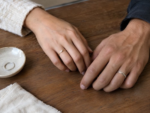 Two hands showing a promise ring worn on the left ring finger and a silver promise ring on the right ring finger